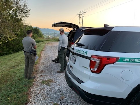 A US Park Ranger, Special Agent, and another officer have an early morning conversation near their vehicles. NPS photo.