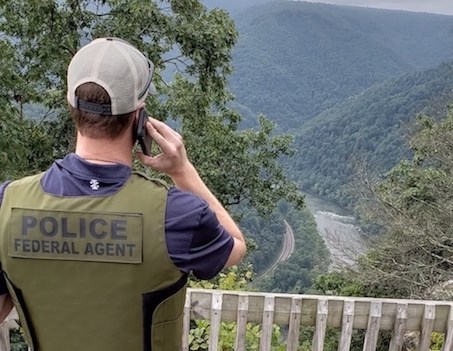 A Special Agent with the NPS Investigative Services Branch speaks on a mobile phone while overlooking a river.