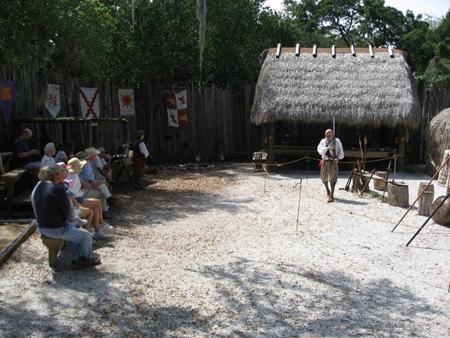 Costumed interpreter demonstrating sixteenth-century European weaponry to De Soto National Memorial visitors at the park's reconstructed Camp Uzita