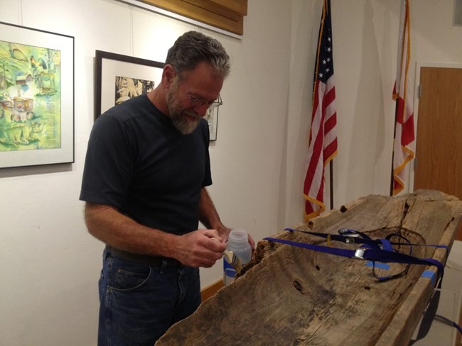 Conservator treating a Seminole canoe on exhibit at Big Cypress National Preserve