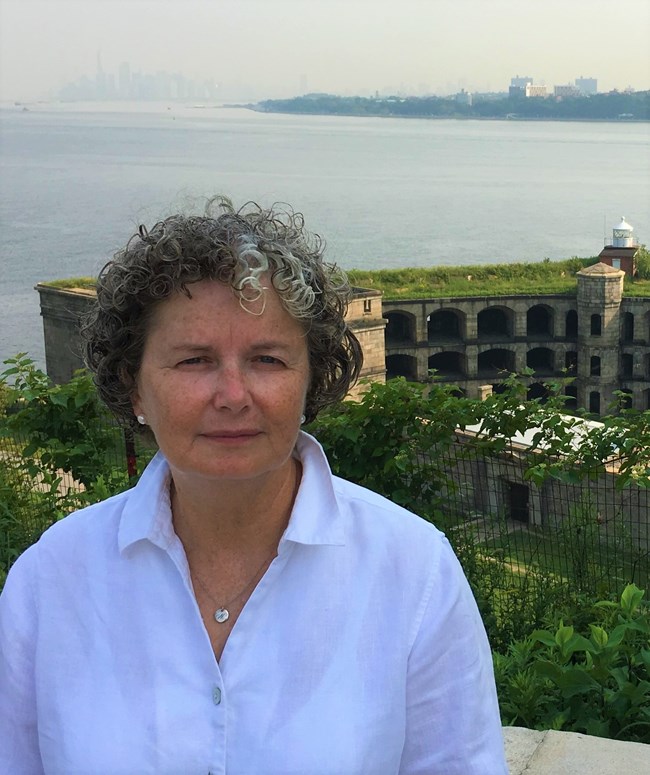 A woman stand at an overlook, with an old fort below.