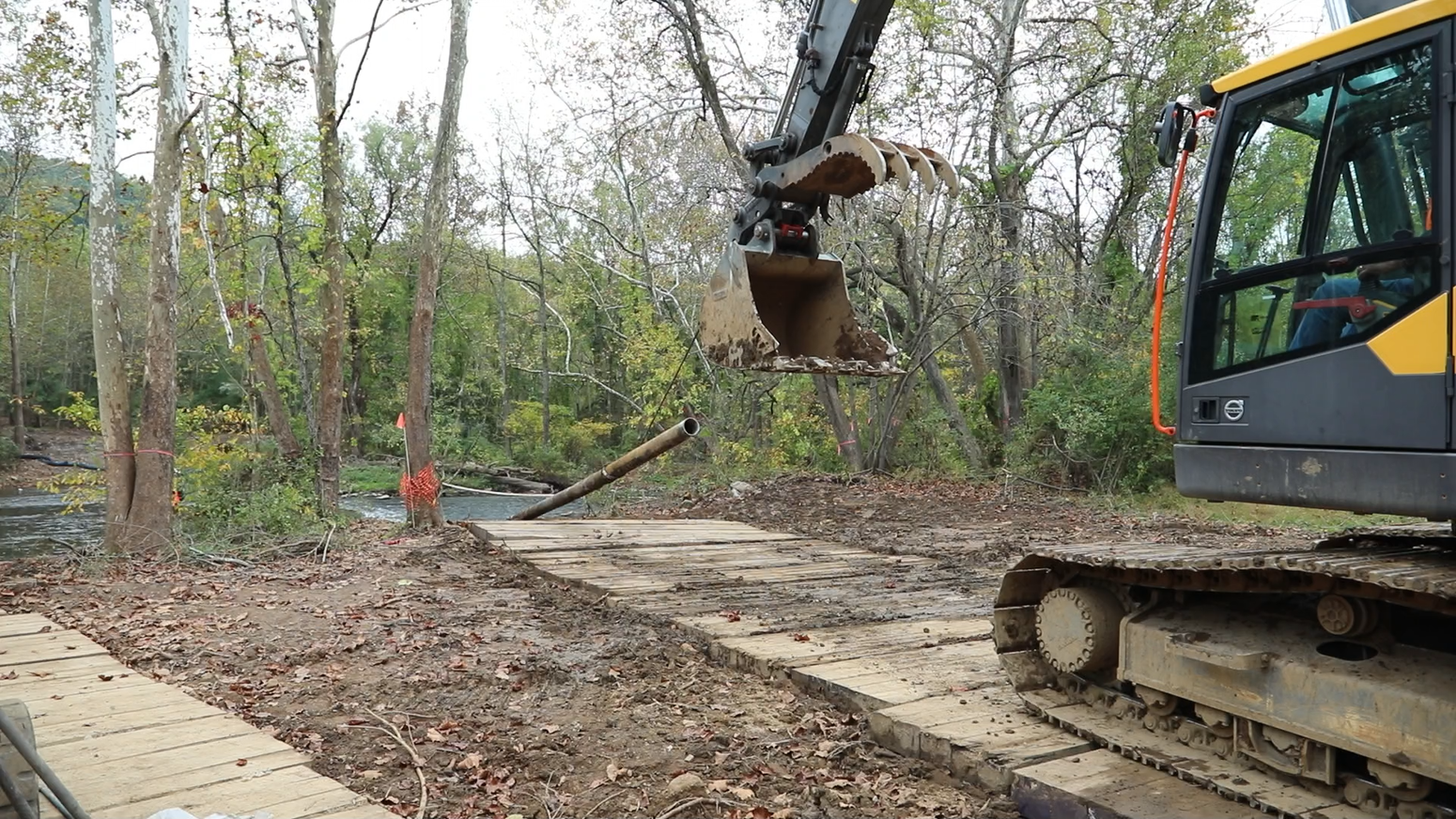 A large piece of equipment lifts a long metal pipe