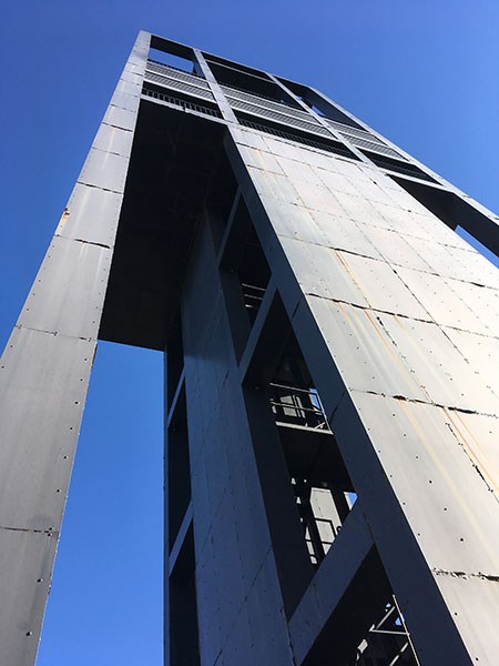 The Netherlands Carillon is a gray metal rectangular structure, standing against a bright blue sky.