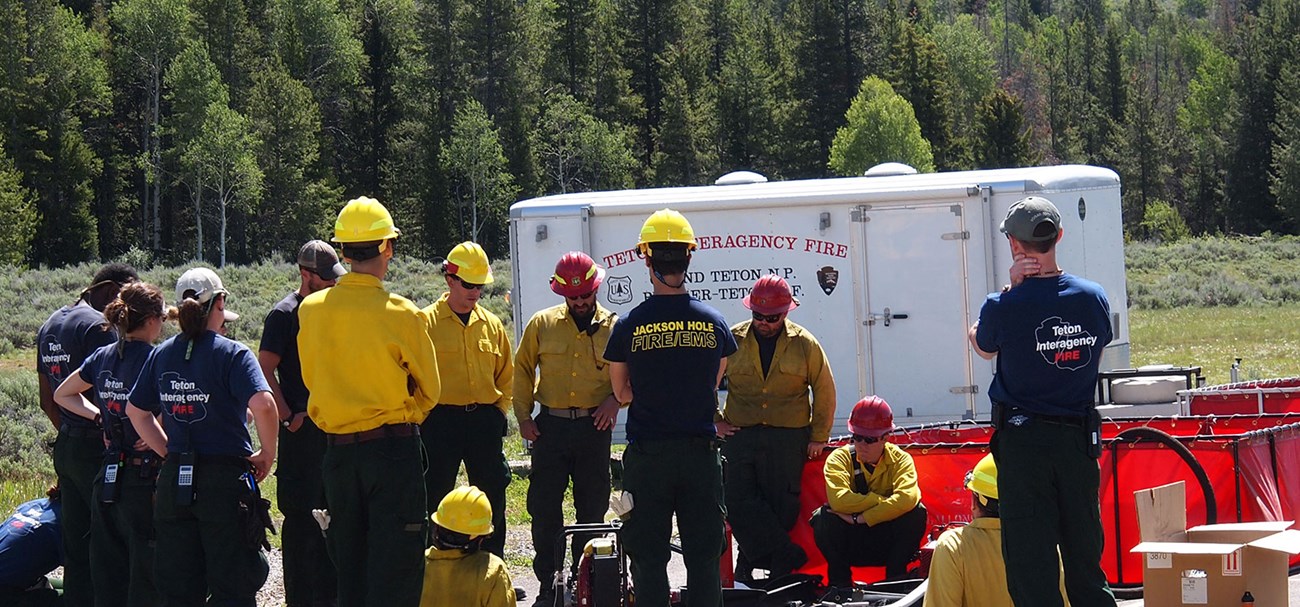 Interagency firefighters gather for a briefing during an outdoor wildland fire training.