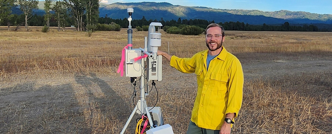 A man in a yellow shirt stands next to a monitoring unit.