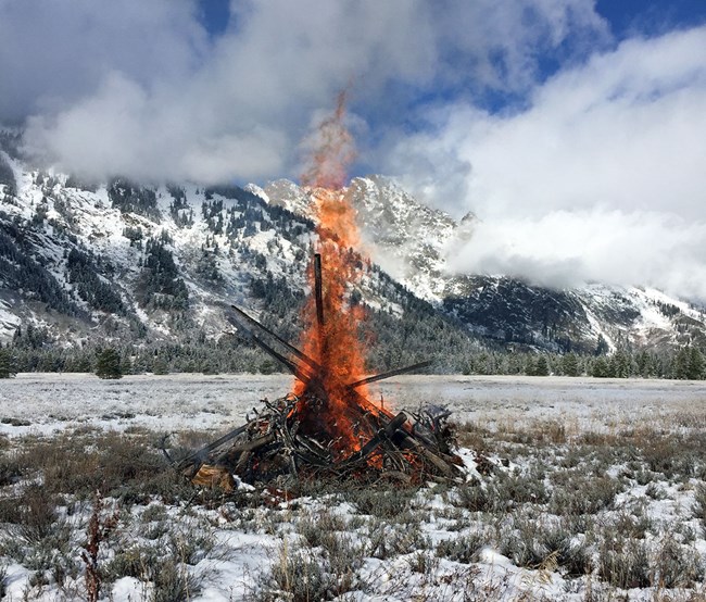 slash pile burning in the sunny snowy scenic mountains at Grand Teton National Park