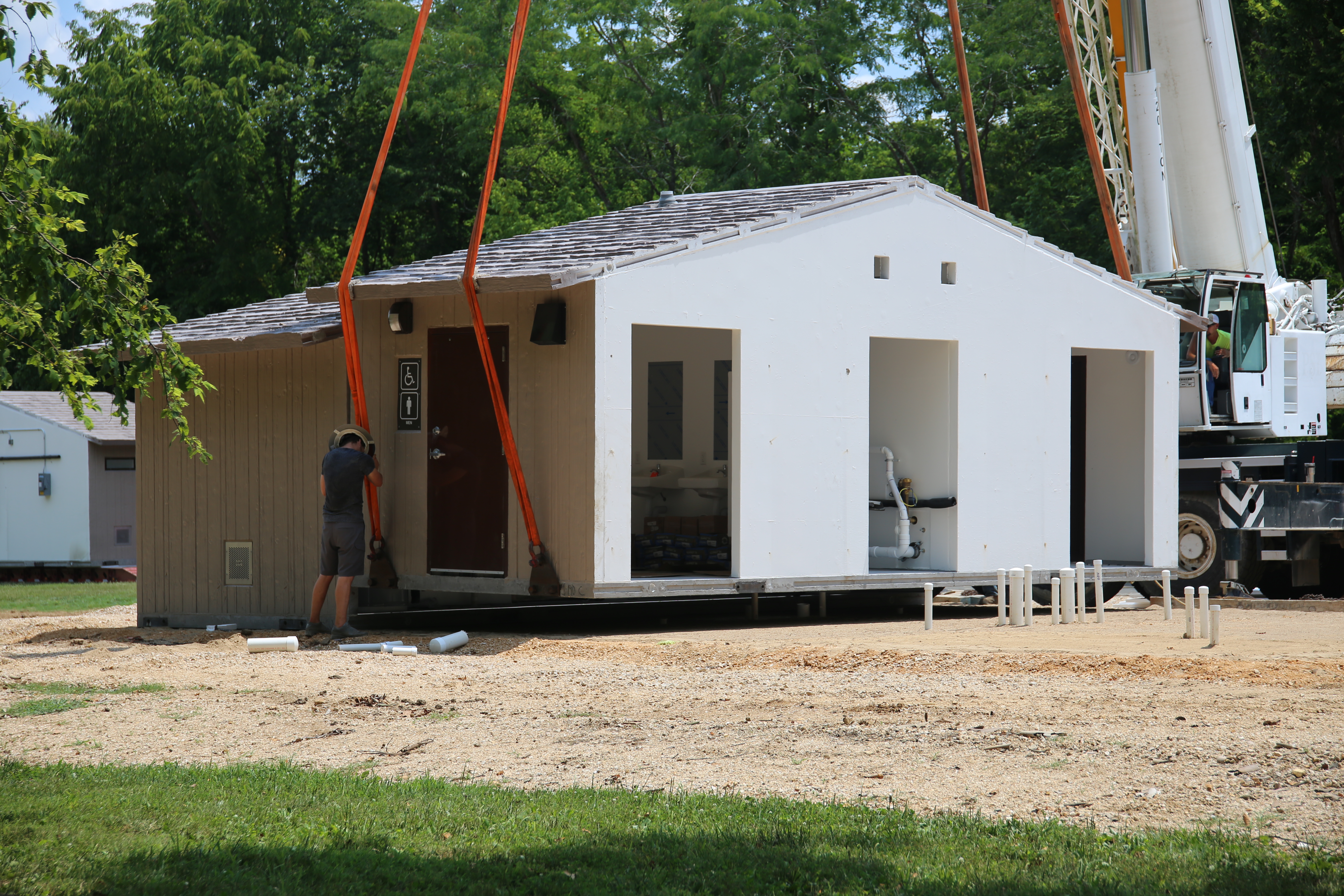 A flooded campground with brown water. In the distance, in the flood waters is a stick built building halfway submerged.