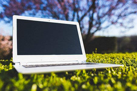 a white laptop sitting in the grass