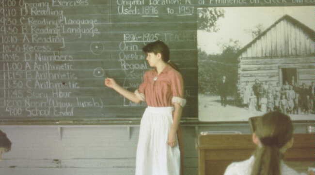 School teacher dress is period style clothing at chalkboard at school