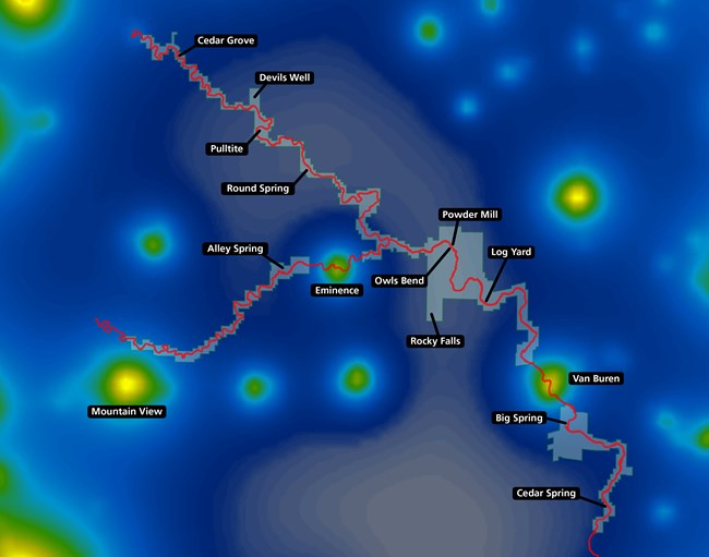 A map showing the park boundary of Ozark National Scenic Riverways and the Current and Jacks Fork Rivers imposed over a light pollution heat map of the surrounding area, with population centers appearing yellow/green and fading to blue in darker areas