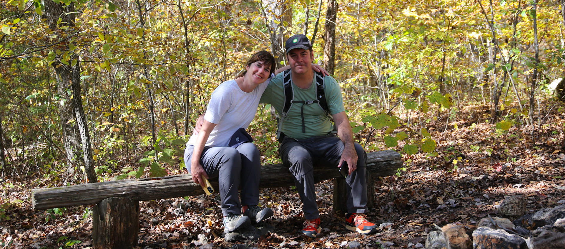 A man and woman sit on a makeshift bench along the Ozark Trail.