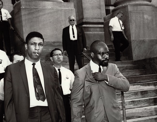 Rubin "Hurricane" Carter exiting the Paterson courthouse after a portion of his trial. Standing right (photo left) is John Artis