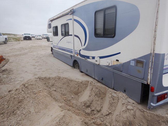 A large RV stuck in the sand.