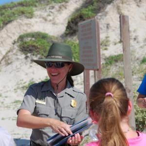 A park ranger talking to a group on the beach.