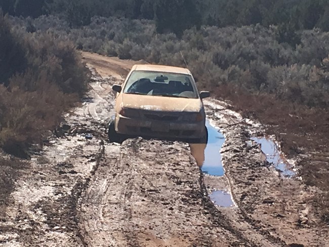 Car stuck in deep water and mud on an unpaved road