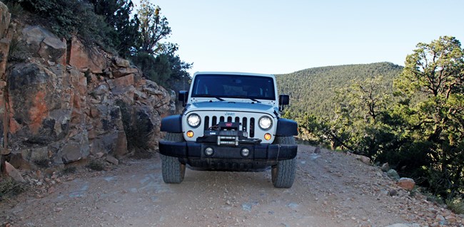 Jeep on narrow mountain dirt road with no room to pass