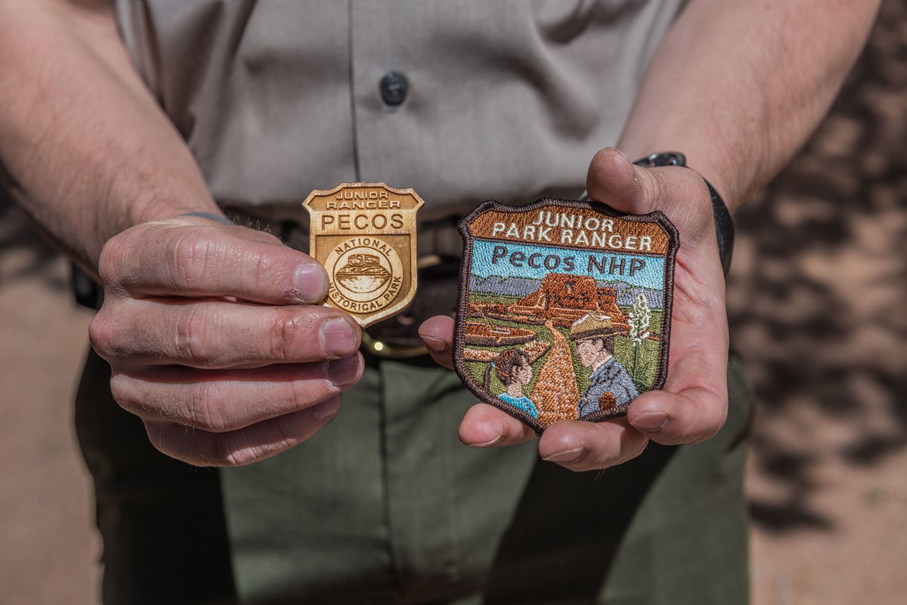 A ranger holds Pecos National Historical Park badges and patches for the Junior Ranger Program.