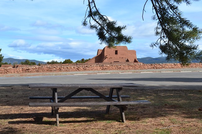 A picnic table with the remains of an old building in the background.