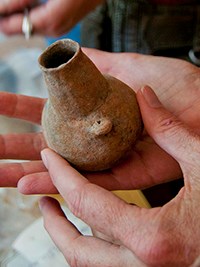 hands holding a small clay pot