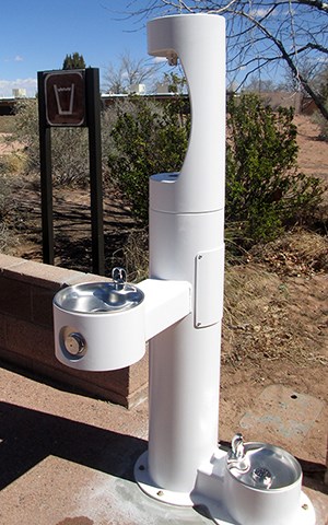 tall white water fountain with faucet at waist high and groundlevel