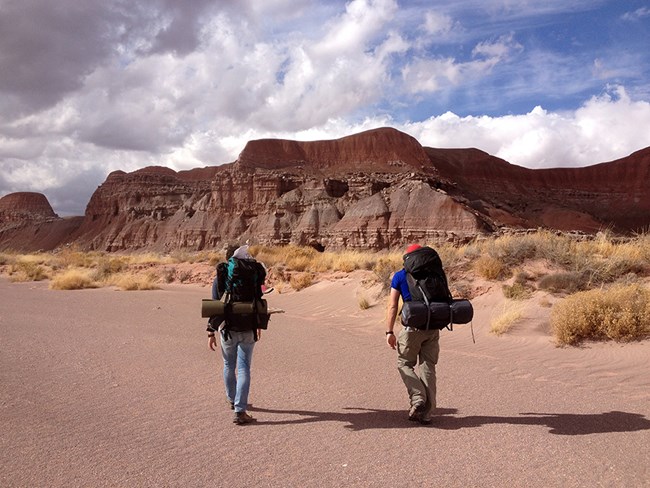 backpackers in wilderness area wash with red badlands