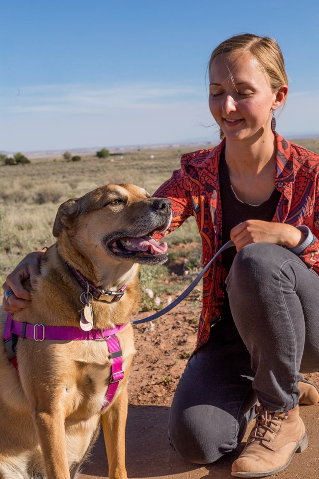 A young woman pets a happy doggo.