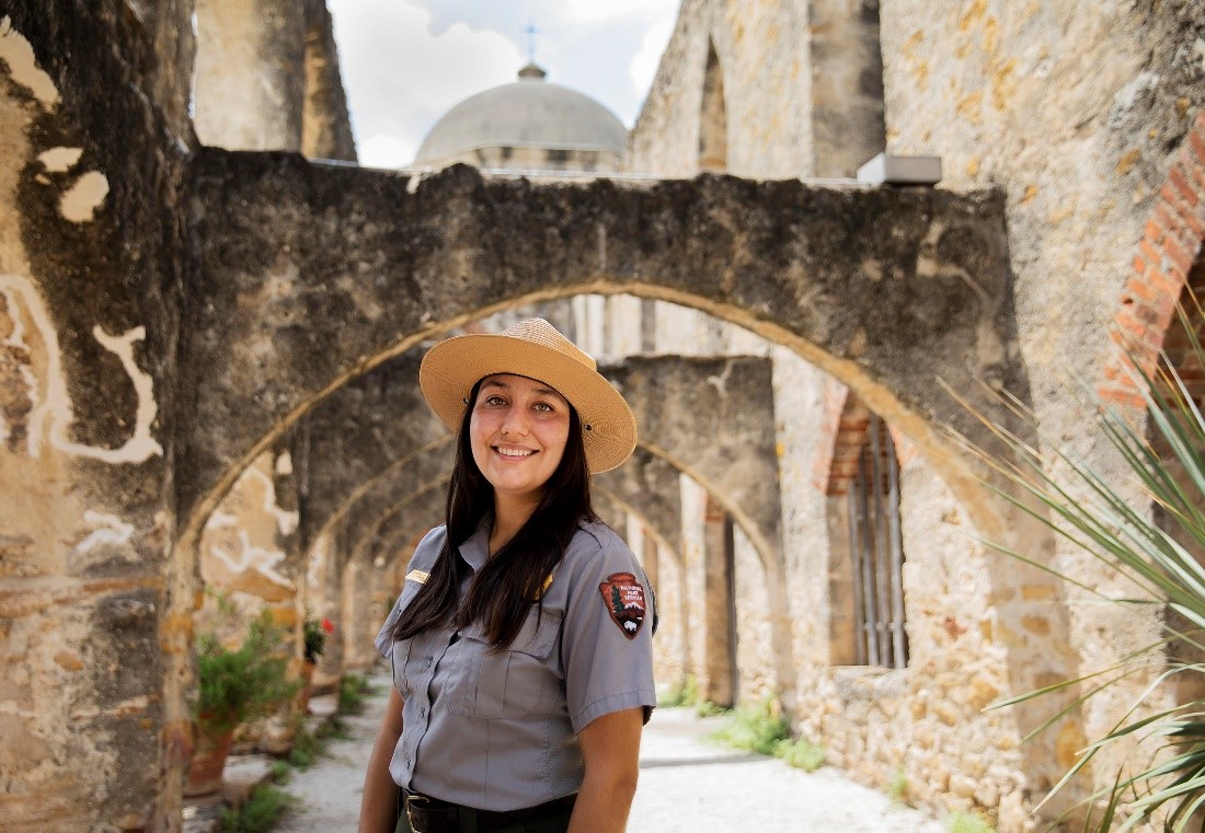 park ranger smiles under stone arches.