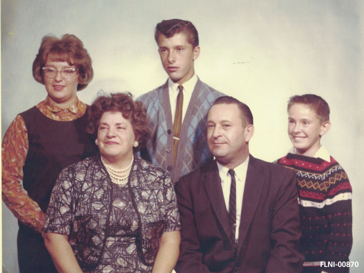 A family portrait with a young woman on the left, an older man and woman and two younger boys dressed in 1950s clothing