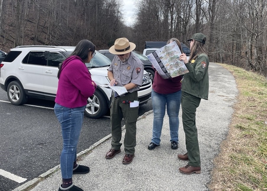 Two park rangers and two visitors interacting.