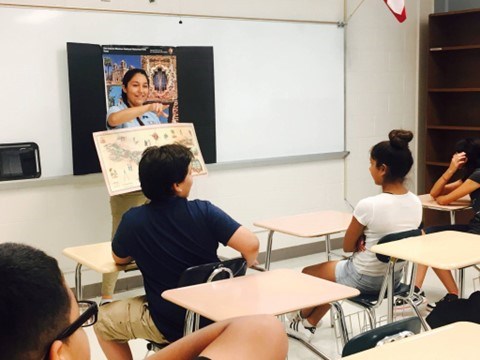Women presenting in front of a classroom of children.