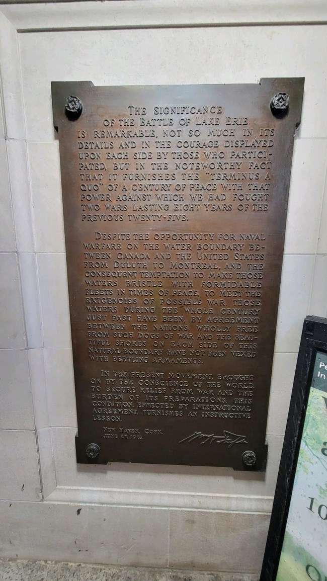 A bronze tablet hung on a marble wall that is titled, The Significance of the battle of Lake Erie.