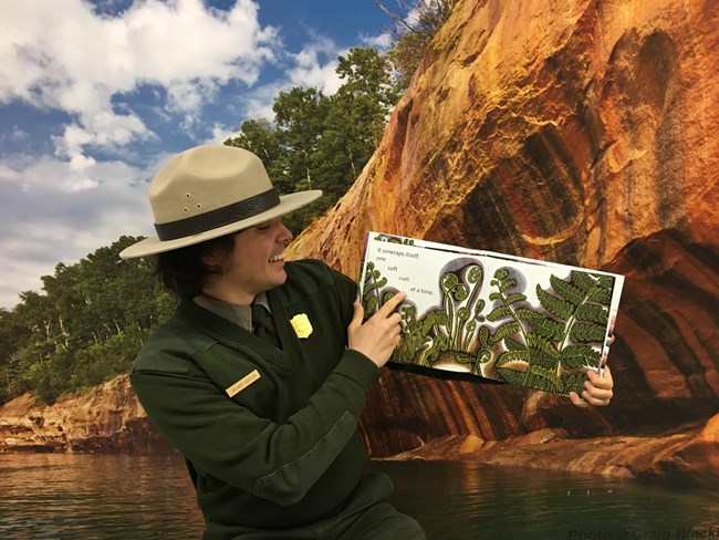 Ranger holding a children's storybook, getting ready to read to an online audience.