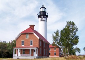 Au Sable Light Station stands guard over Lake Superior with its red brick keepers house and white light tower.