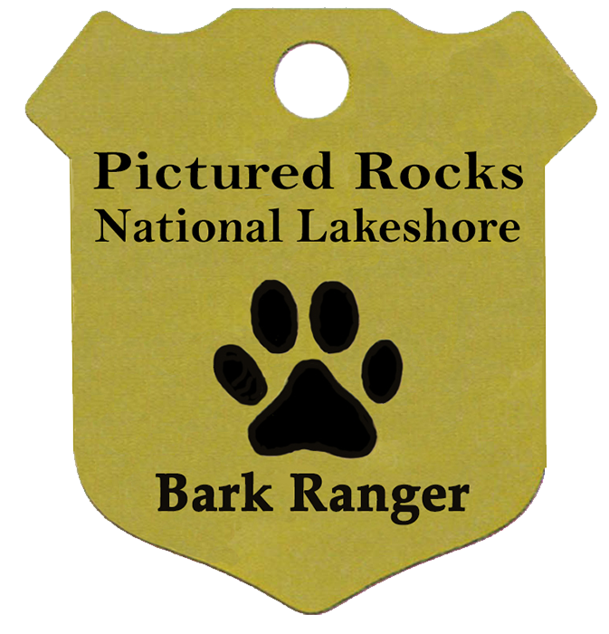 Badge-shaped dog tag with a paw print in the center and the words Pictured Rocks National Lakeshore Bark Ranger Tag