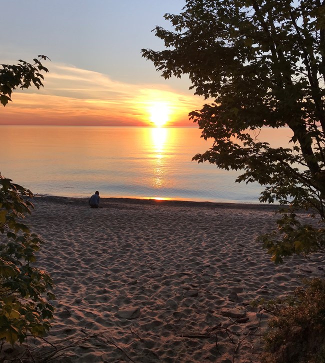 Visitor watching a sunset over Lake Superior at Hurricane River.