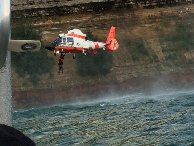 Coast Guard Helicopter hoisting kayaker from Lake Superior along cliffs in Pictured Rocks National Lakeshore