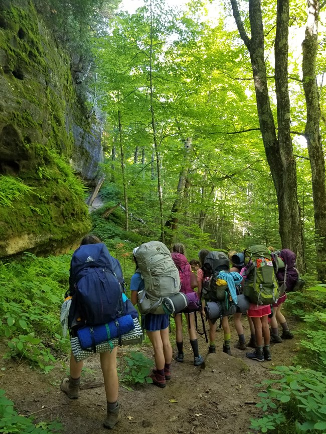 A group of backpackers on the North Country Trail standing on trail in forest