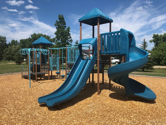 A bright blue and brown playground with slides, climbing bars, and bridges