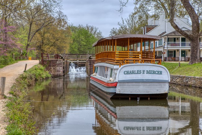 A boat sitting in a watered canal with a historic white building in the background