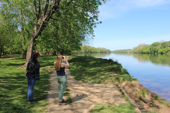 Two visitors looking through binoculars over water