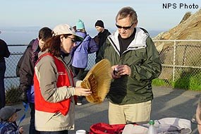 A Winter Wildlife Docent with baleen talking to visitor at the Point Reyes Lighthouse Observation Deck.