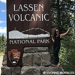 Point Reyes Social Media Team member Rachel standing on the base of Lassen Volcanic National Park's entrance sign.