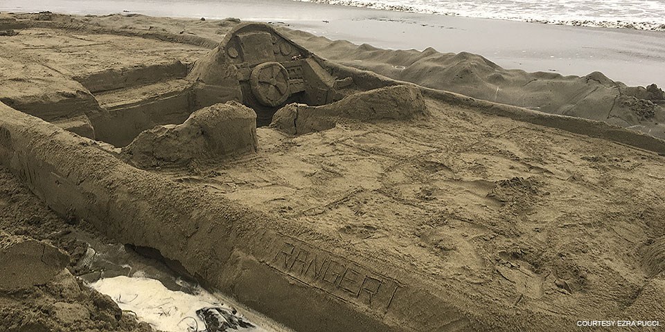 A 22-foot-long, nine-foot-wide sand sculpture of a motorboat riding low in the water (sand).