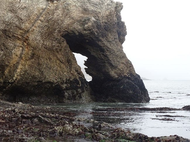 A small keyhole passage in a small headland surrounded by water.