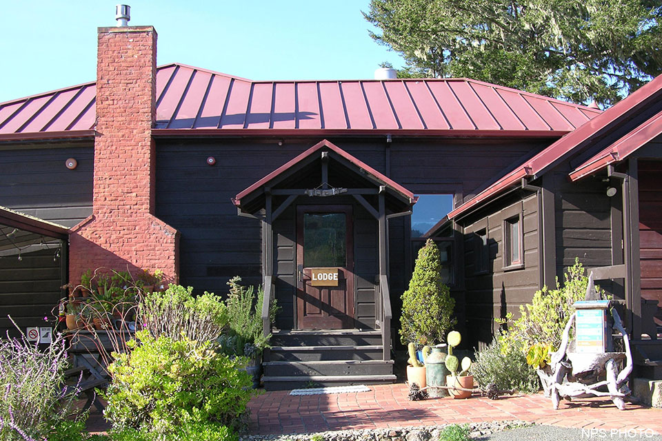 A photo of the main entrance to a one-story, brown-sided, red-roofed building.