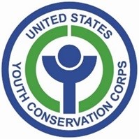 Logo with a blue outer circle. Curved text reads, "United States Youth Conservation Corps" in blue text in all caps. Inside this text are two green semi circles. Inside of the green semi circles is a small blue circular person figure
