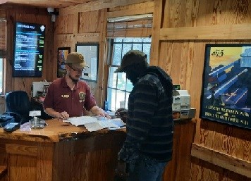 Volunteer show a visitor a map of the trails at the desk in the visitor center