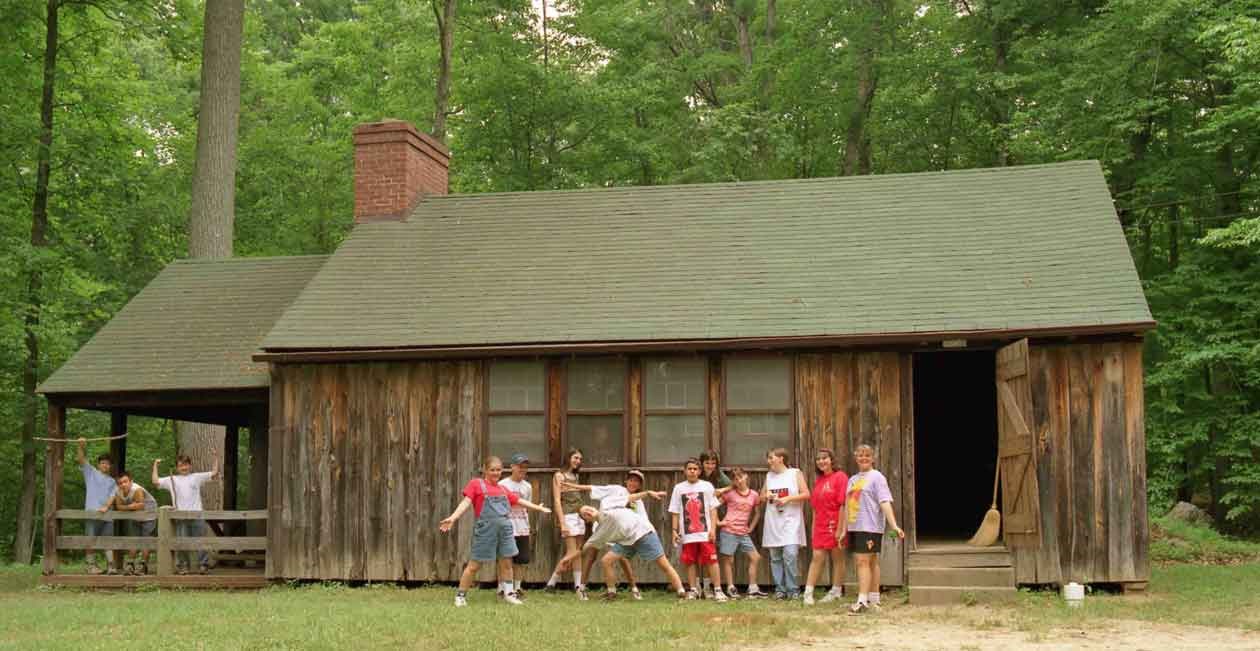 children stand in front of cabin
