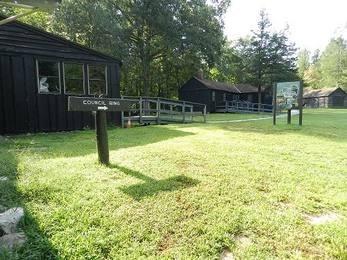 Two wooden cabins with information signs have a path through the grass between them