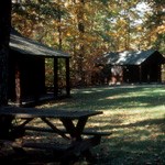 2 single cabins and picnic table in a grassy meadow in the fall